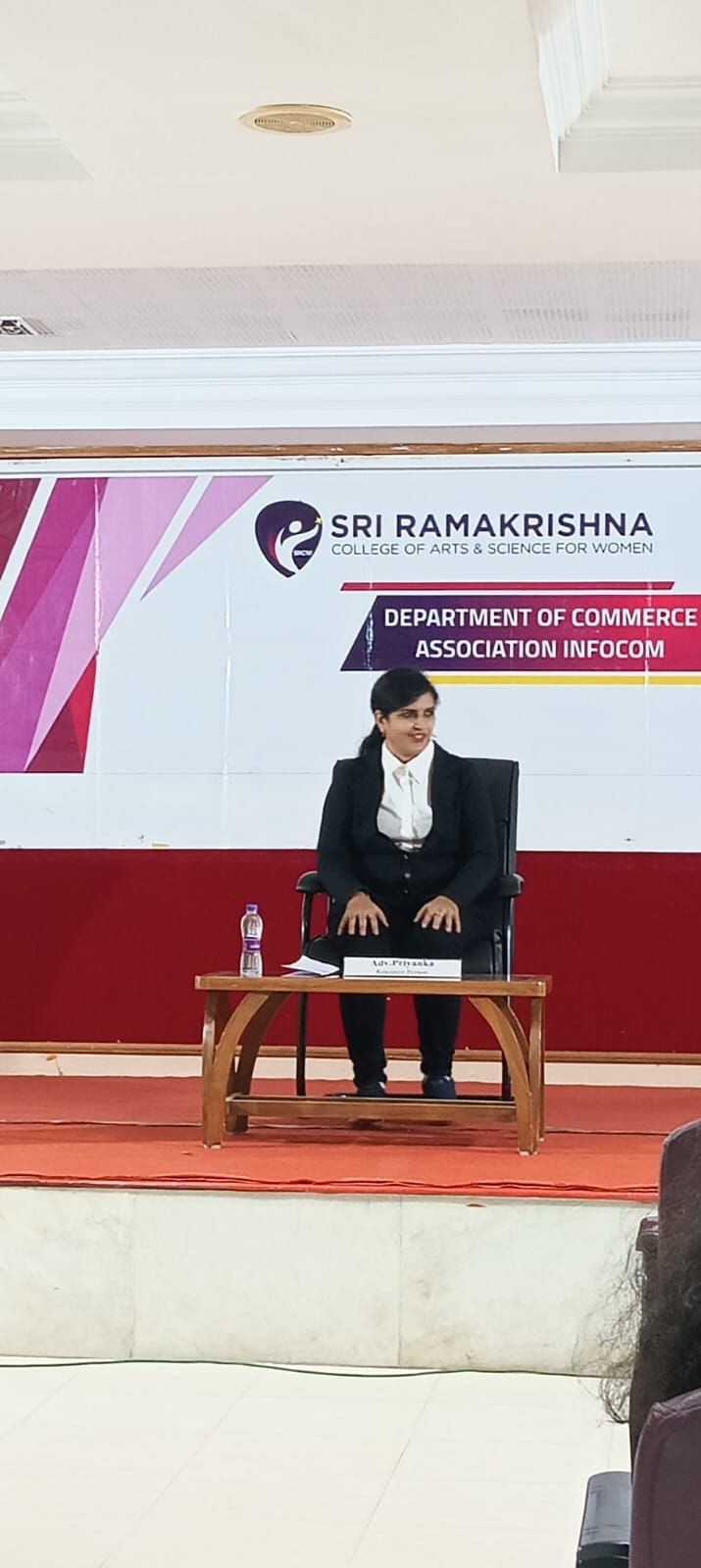 Advocate Priyanka seated on stage at a college event
